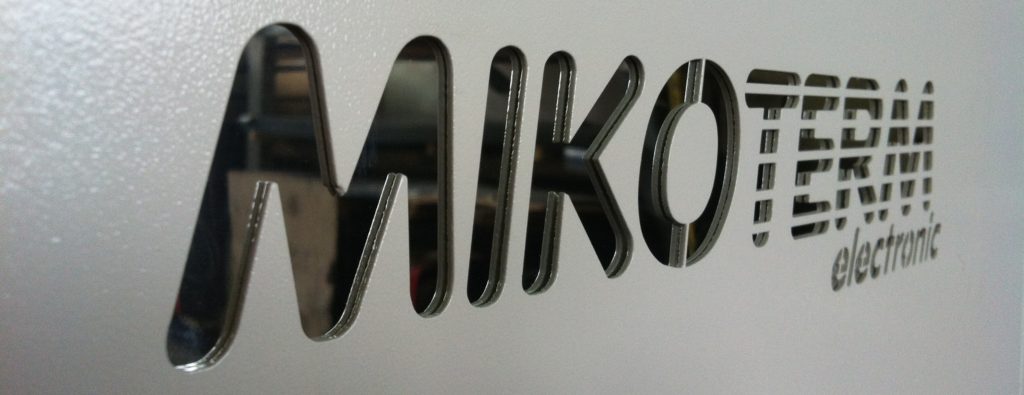 Mikoterm logo ugraviran u zid, crne boje naspram sivog zida.